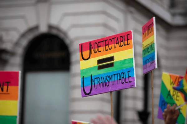 Undetectable equals Untransmittable written in black on a rainbow painted, homemade sign.